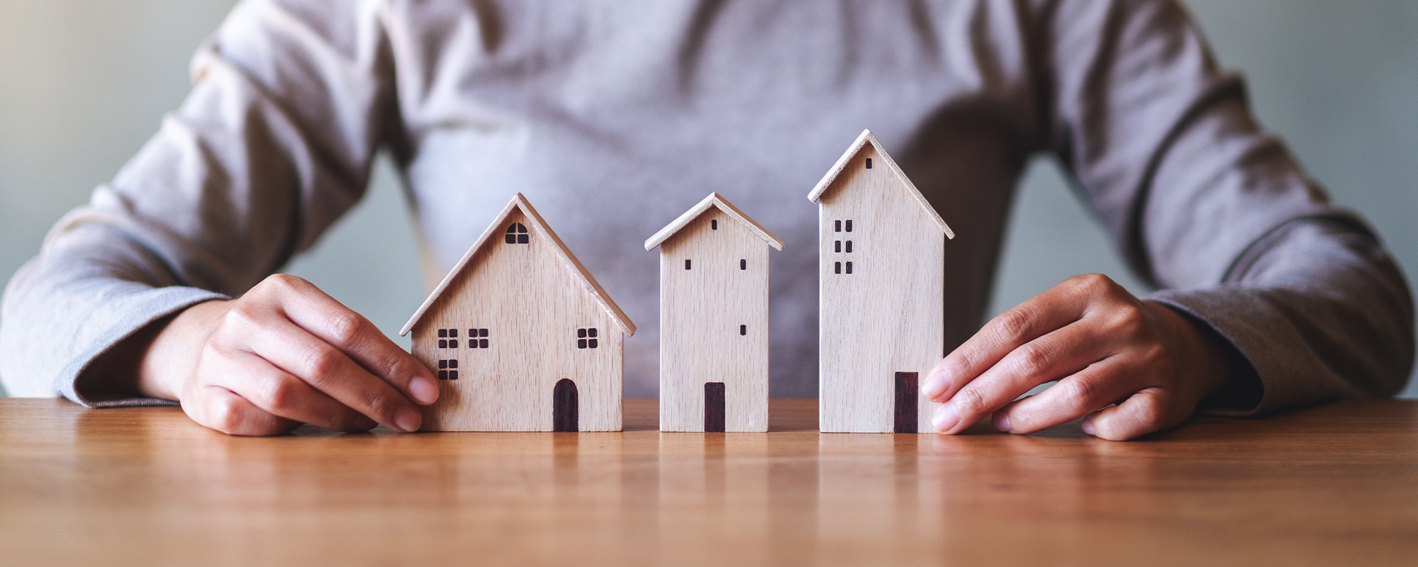 closeup image of a woman holding wooden house models on the table