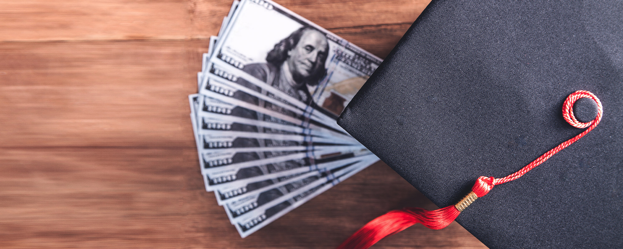 graduation hat and money on wooden table.